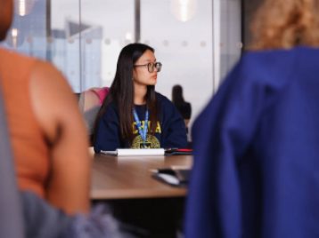 UM student sitting at a conference table looking off camera, in Madison Square Garden's meeting room.